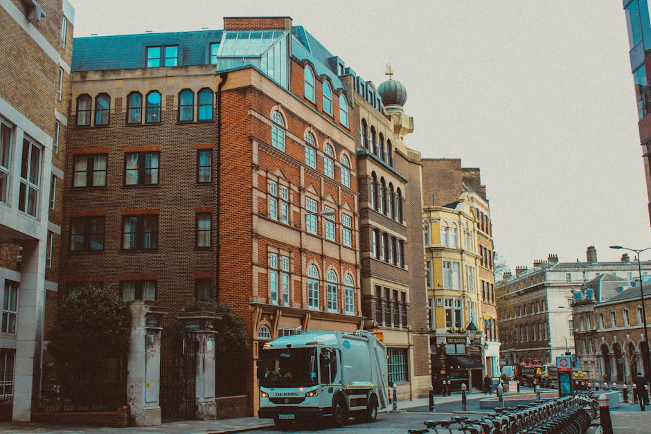 A street scene in West Kensington showing a white moving van parked outside a multi-storey brick and stone building with large arched and rectangular windows, typical of Victorian or Edwardian archite