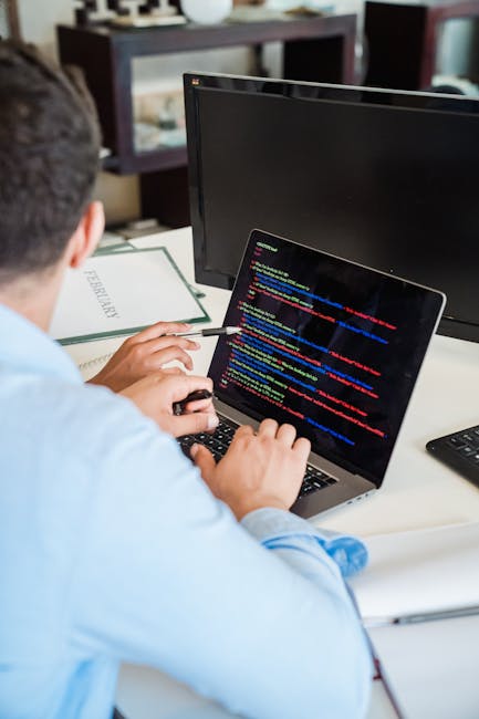 Photograph depicting a computer screen with blurred, multicoloured source code in a text editor or integrated development environment, showcasing lines of programming syntax including functions, varia